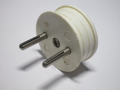 White bakelite plug with a rounded front. The pins are split and not sleeved.